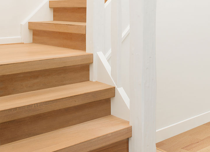 Afgewerkte houten trap met witte leuning