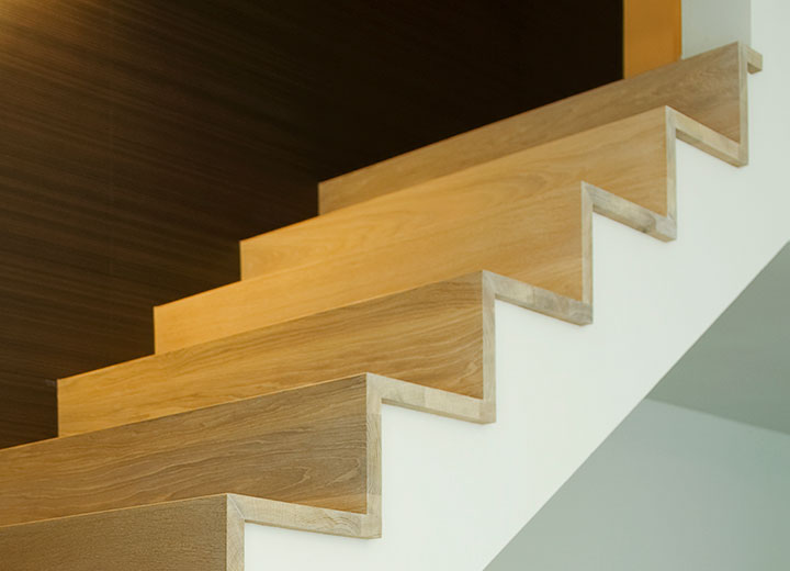 Houten trap met rechte treden tegen een witte wand